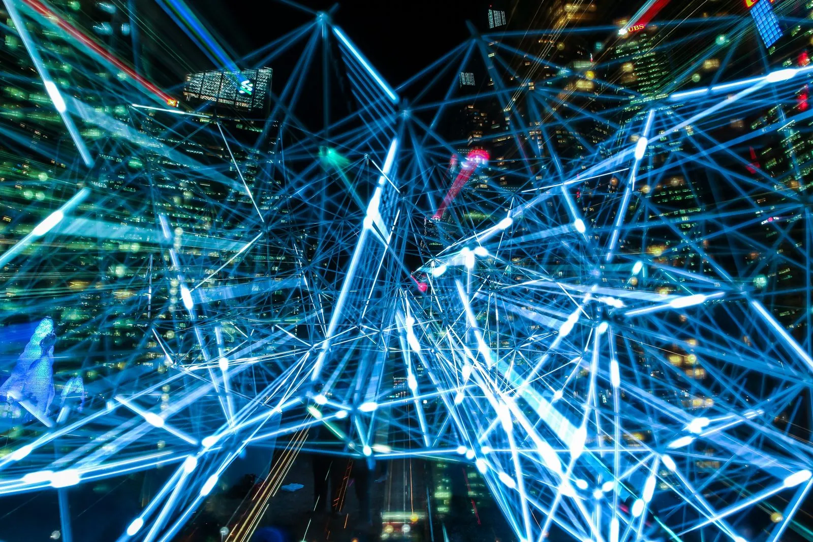 Long-exposure blue light trails crossing a city skyline at night
