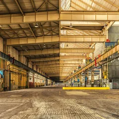 An empty industrial warehouse with yellow railings and overhead lights