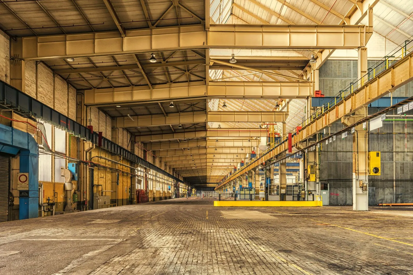 An empty industrial warehouse with yellow railings and overhead lights