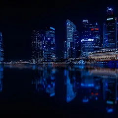 A city skyline lit up at night and reflected in still water