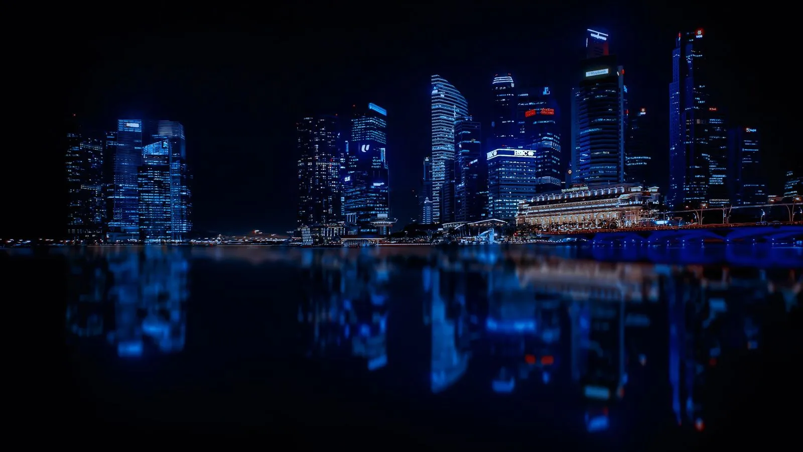 A city skyline lit up at night and reflected in still water