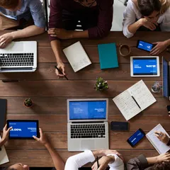 A tabletop view of laptops, notes, and phones during a policy meeting