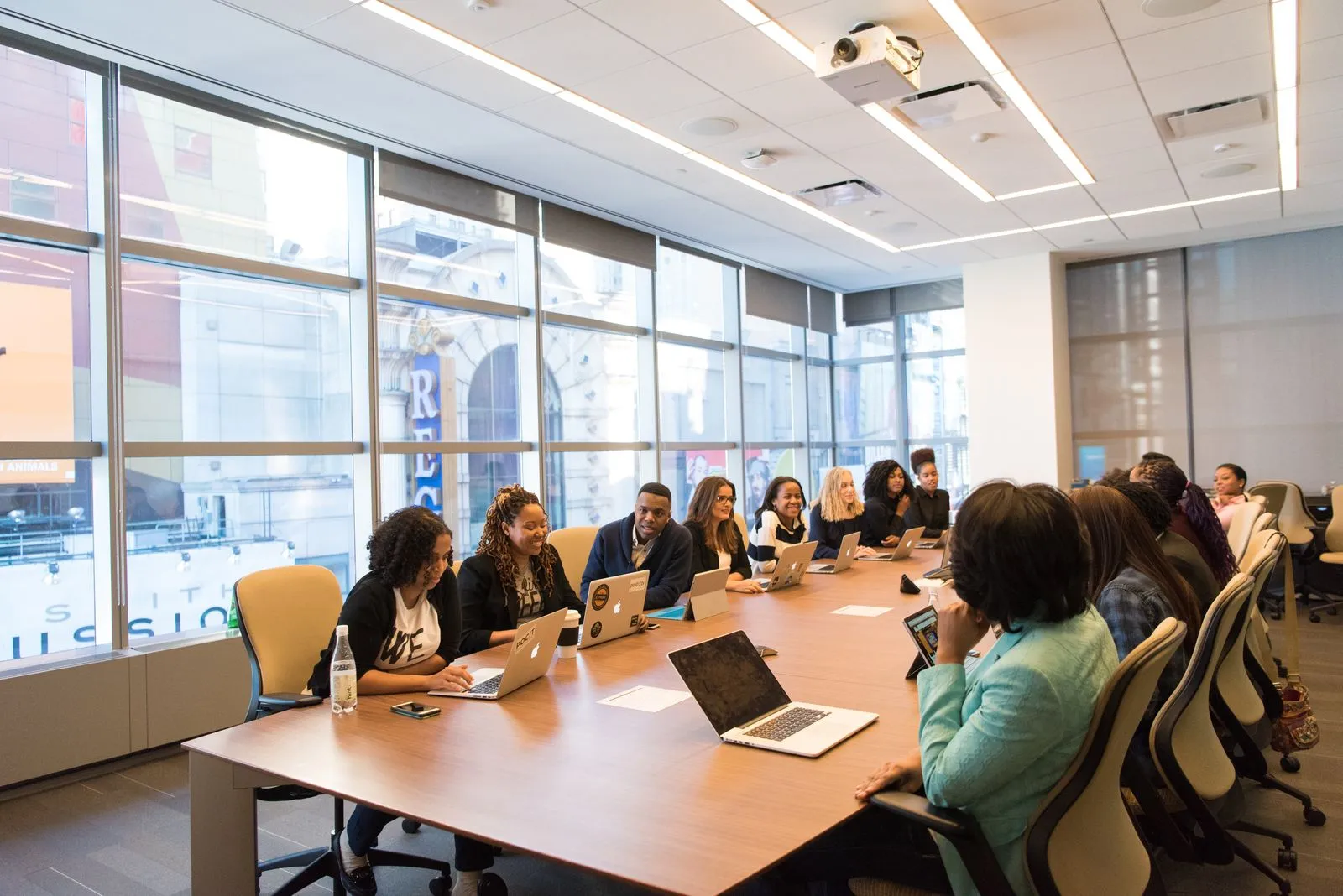 People seated around a long table in a bright meeting room with laptops open
