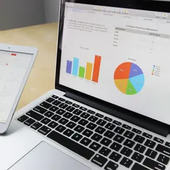 A laptop displaying bar and pie charts beside a tablet showing a calendar