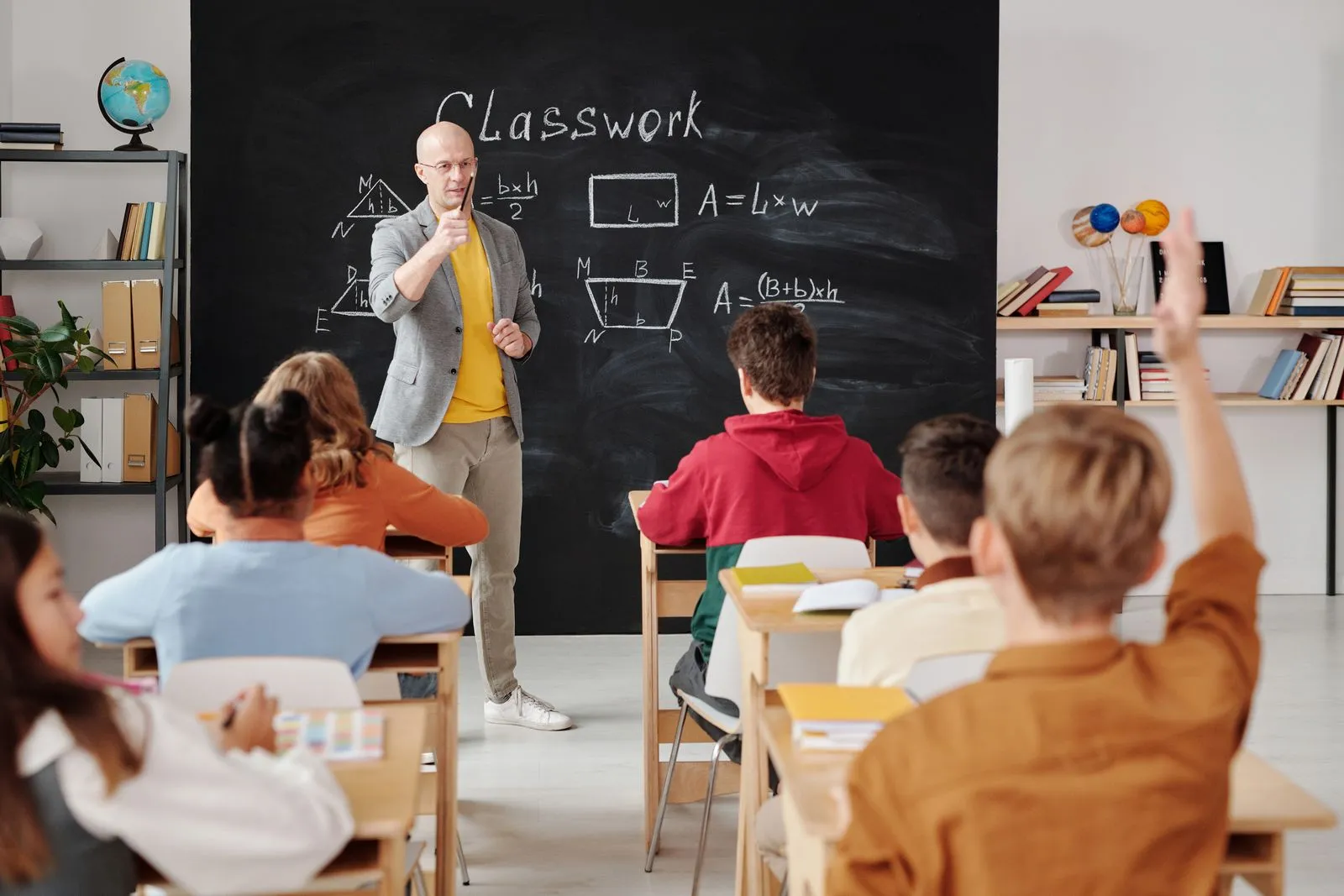 A teacher standing near a chalkboard in a classroom