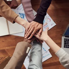 Hands meeting over notebooks and laptops during a strategy session